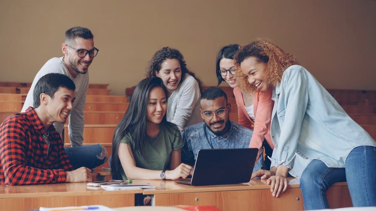 Grupo de estudantes rindo em volta de um notebook
