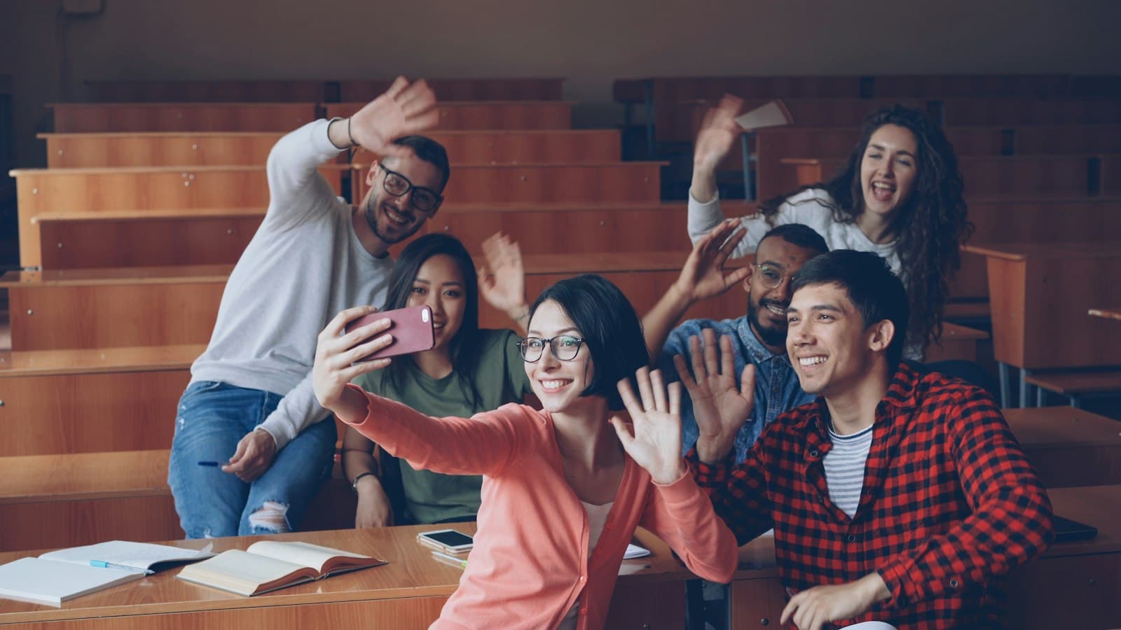 Estudantes sorrindo e tirando uma selfie em sala de aula